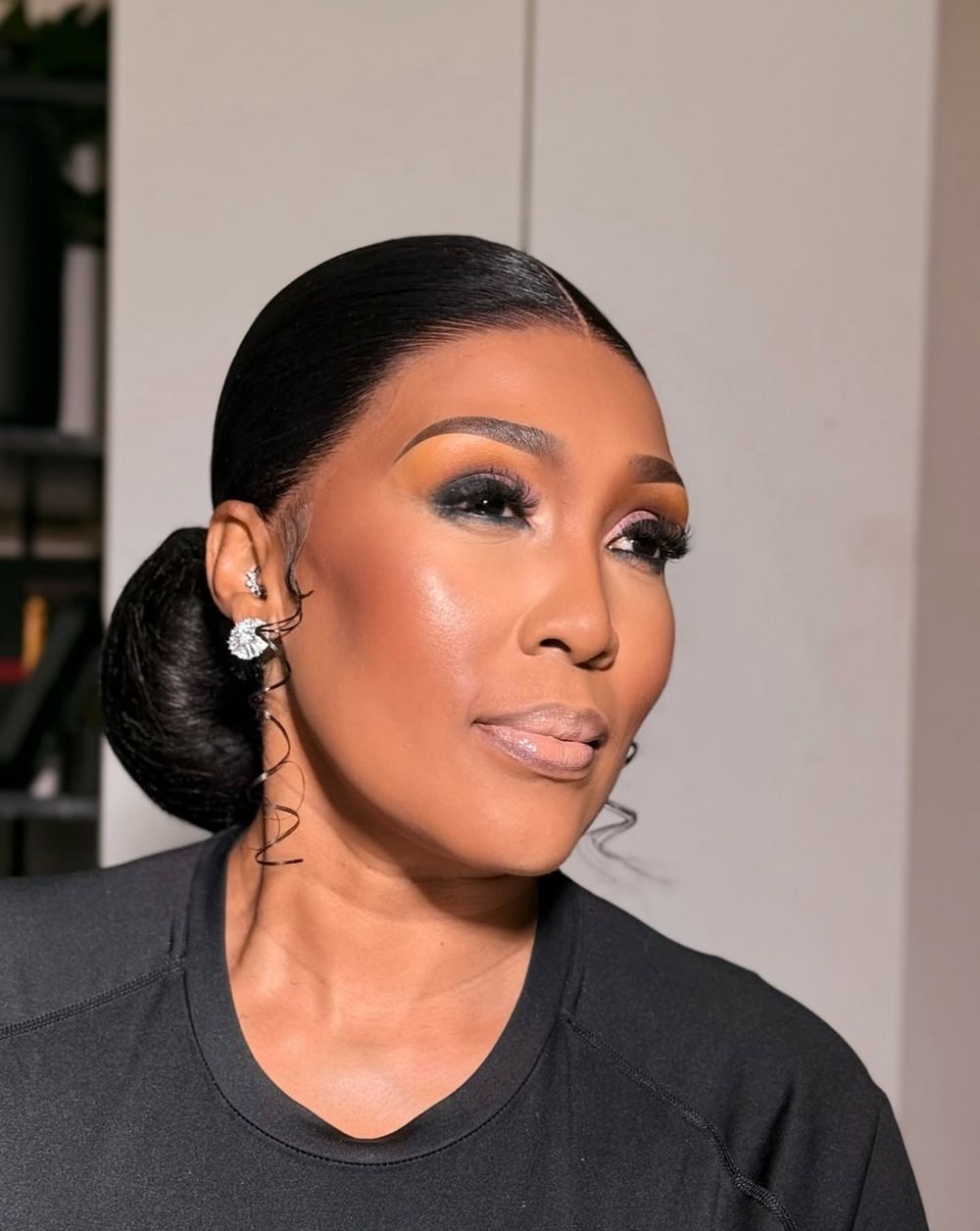Polished low bun with spiral curls and smoky eye makeup